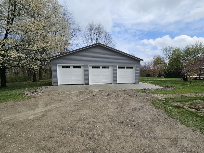 Three-car detached garage with white raised-panel garage doors and window inserts
