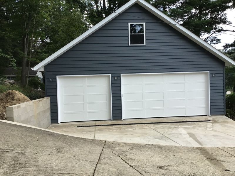 Two white long-panel garage doors on a navy blue detached garage