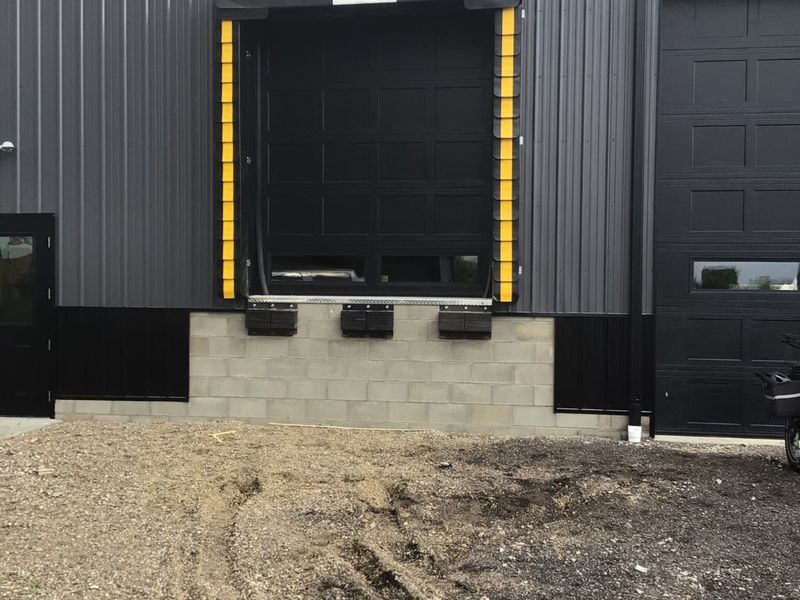 Loading dock door with dock seal and leveler on a black steel commercial building