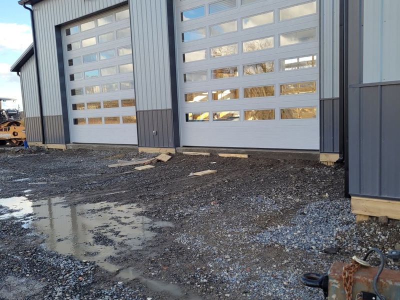 Two tall full-view commercial garage doors with glass panels on a new steel building